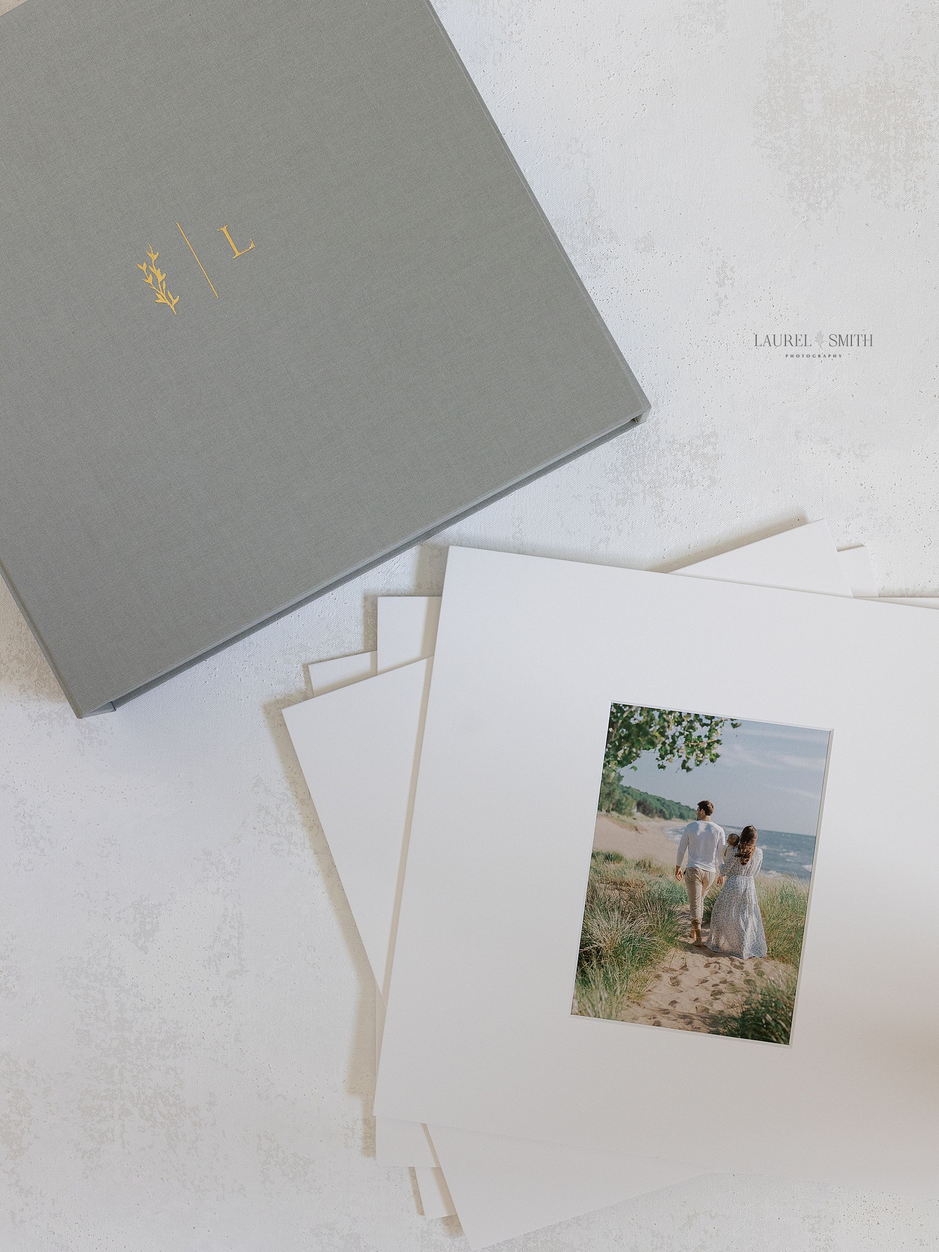 Matted print images of family walking on beach next to folio box.