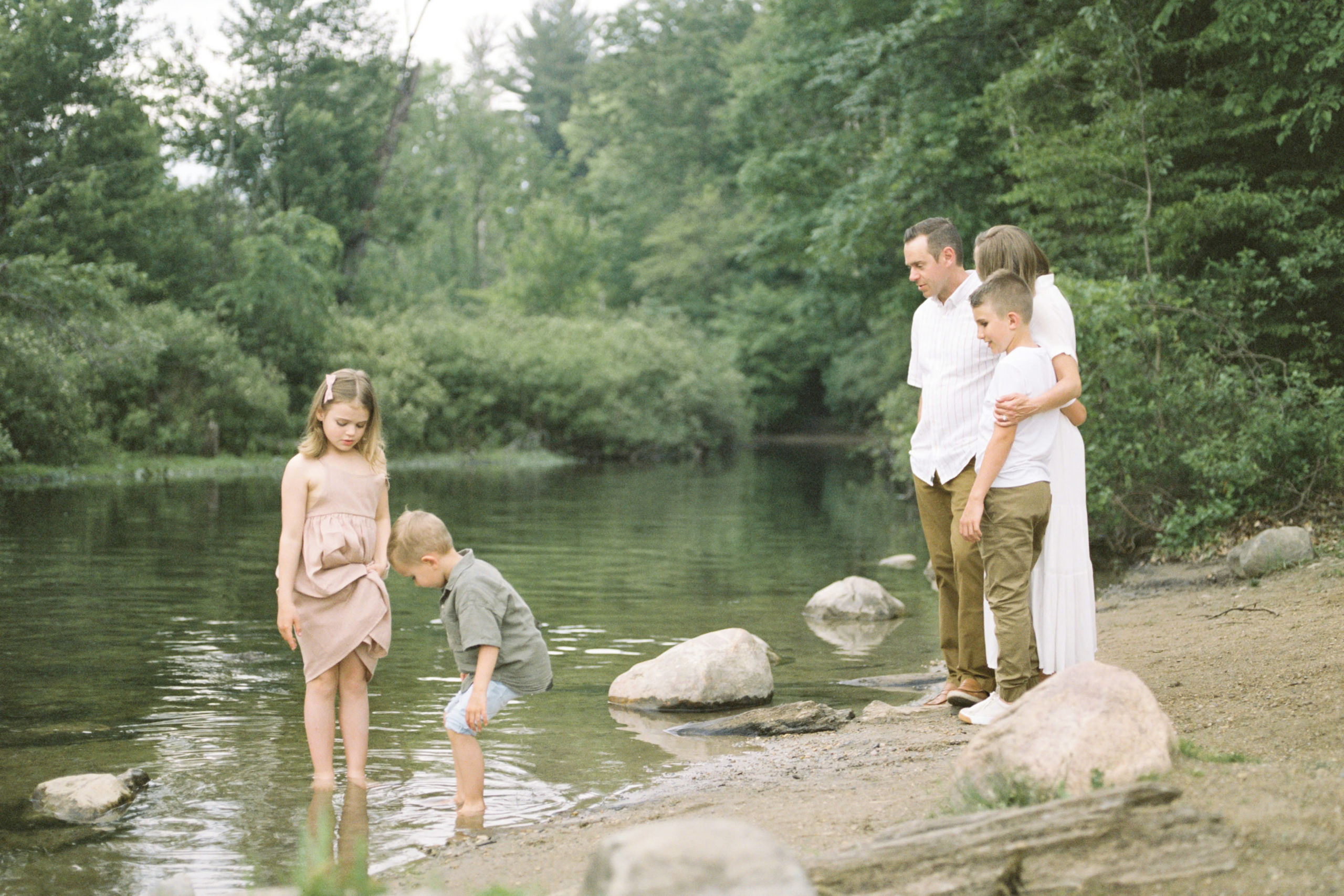 family of 5 playing on the rocks by a creek