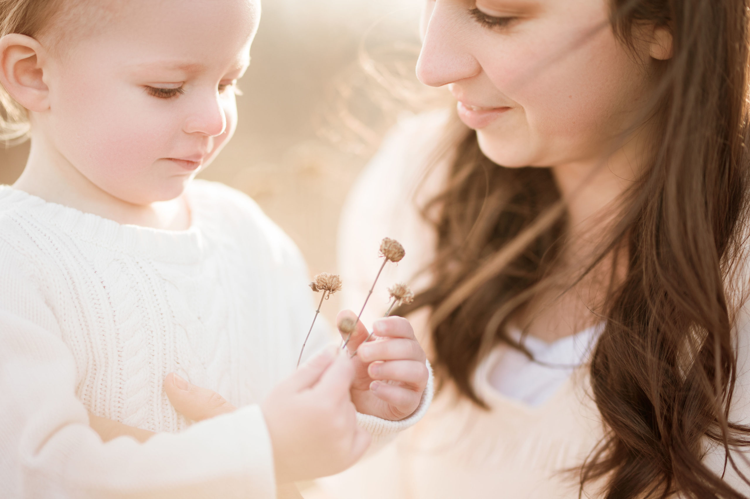 mom and young child looking at a flower
