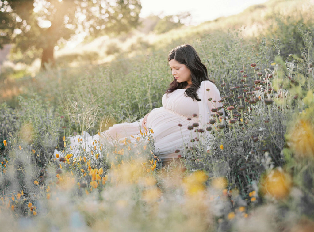 Maternity photoshoot San Francisco highlighting a relaxed mama moment sitting in a field of flowers. 