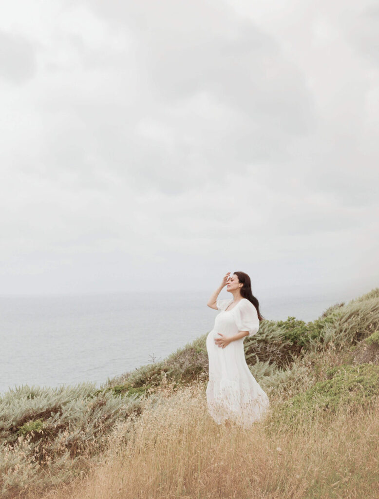 Maternity photoshoot San Francisco capturing solo maternity images of a mama-to-be standing on a hill looking out to the water