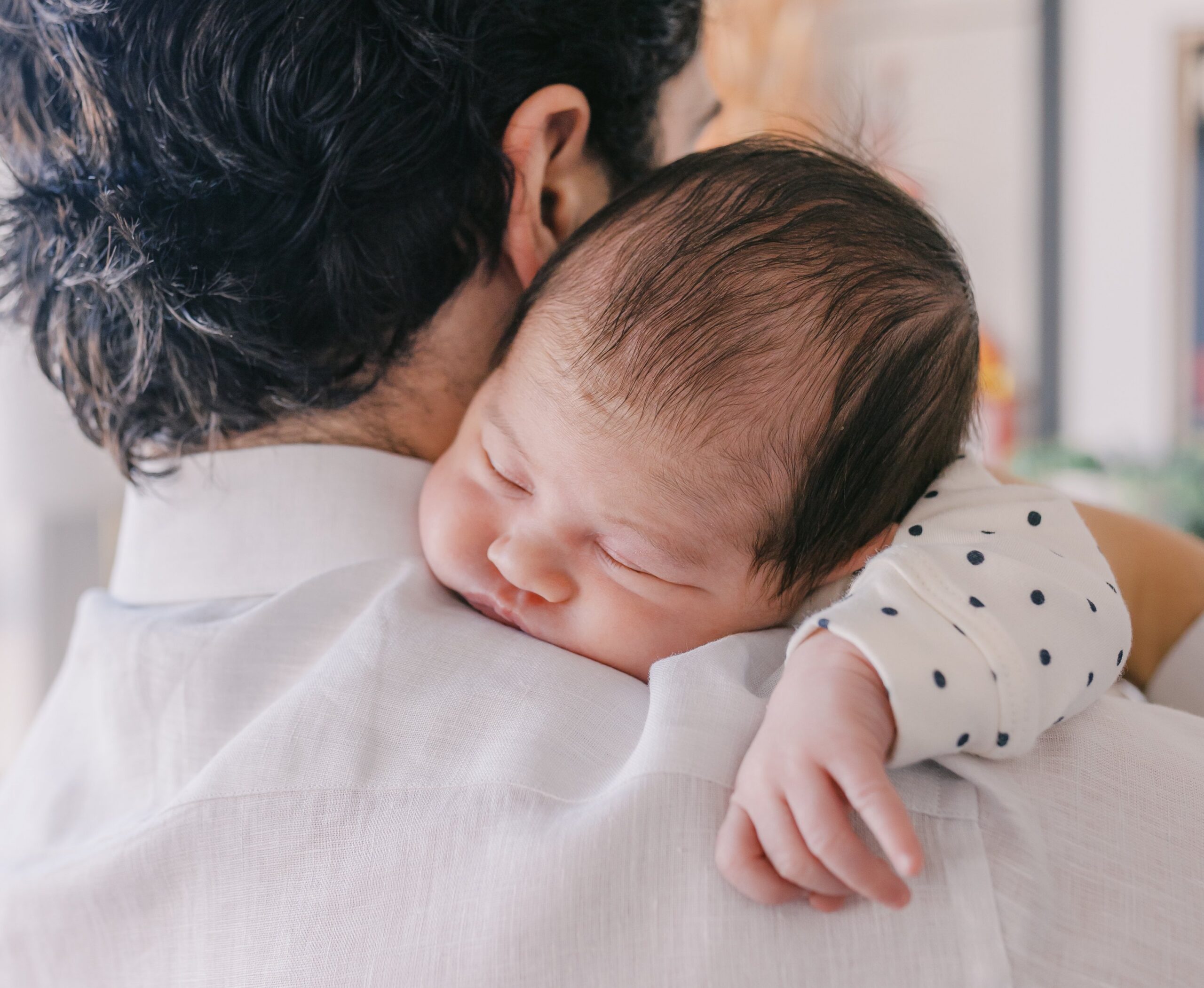 Sleeping newborn resting on a parent’s shoulder, captured in a soft, intimate moment with natural light during a lifestyle newborn photography session in the Bay Area