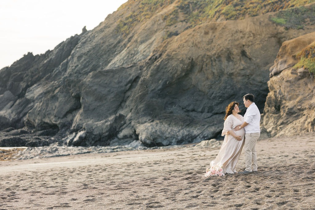 couple lovingly gazing into each other's eyes on rodeo beach ca during their maternity photoshoot