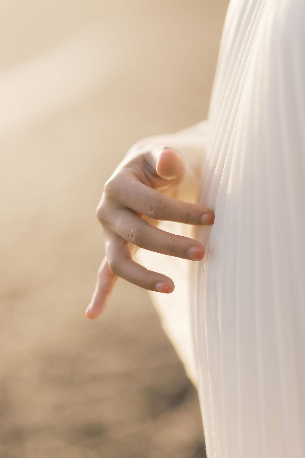 woman's hand softly touching her pregnant belly during her maternity photoshoot at rodeo beach ca