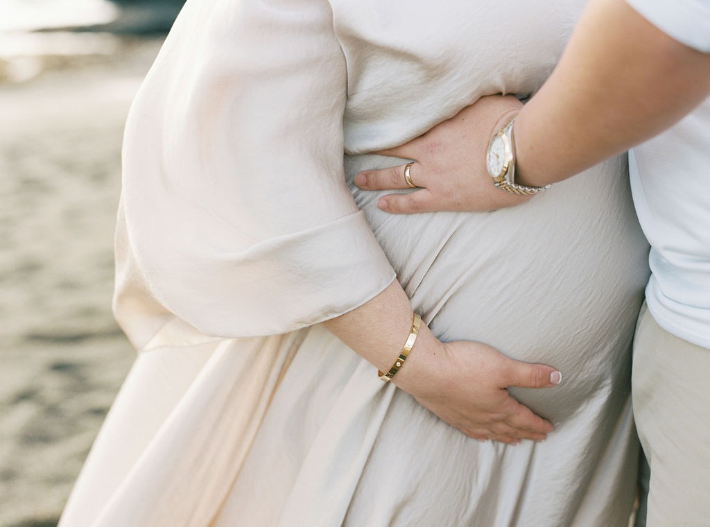 closeup of a man and woman holding her pregnant belly during their rodeo beach san fracisco maternity photoshoot