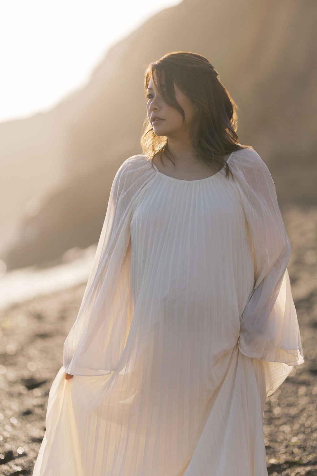 woman walking toward the camera during her golden hour maternity photoshoot at rodeo beach ca