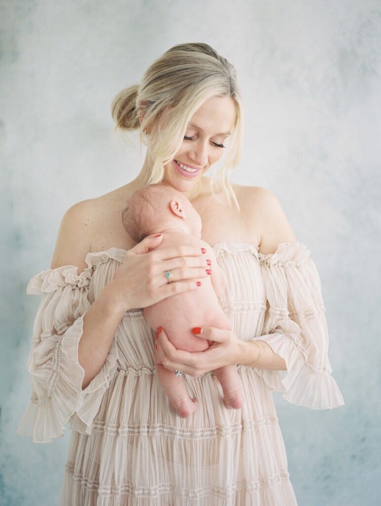 Mother holding newborn baby during the best time for newborn photos in studio. 