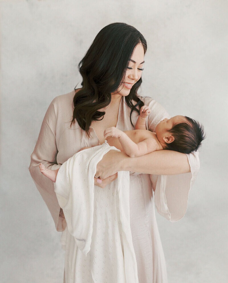Studio newborn portrait showing the best time for newborn photos with mother and baby. 