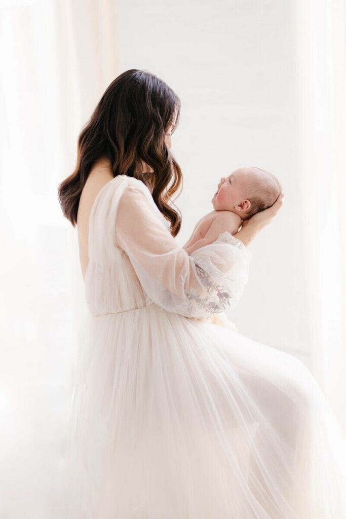 Mother holding newborn baby during the stage when should newborn photos be taken. 