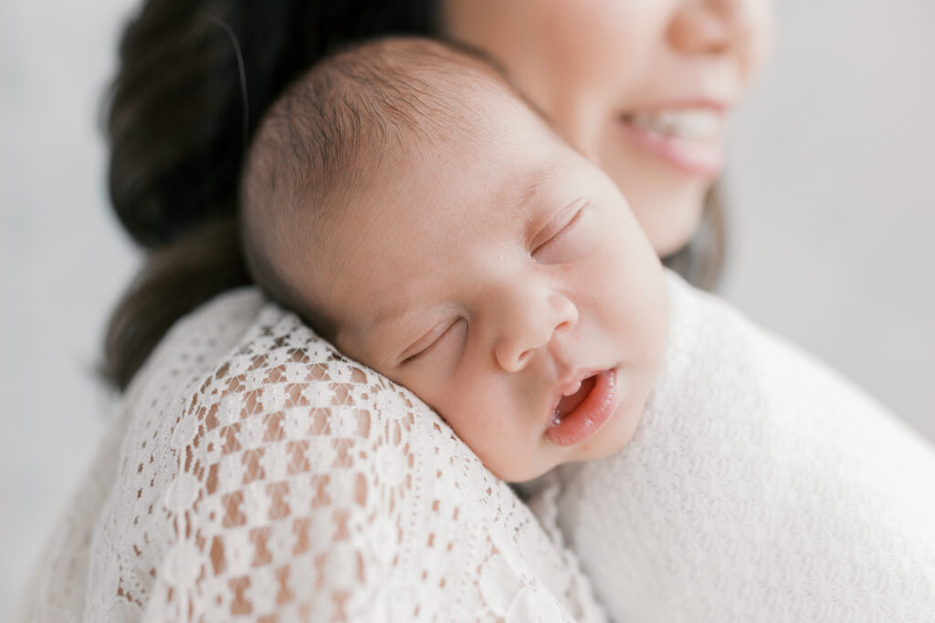 Mother holding sleeping baby during a newborn session showing when to take newborn pictures. 