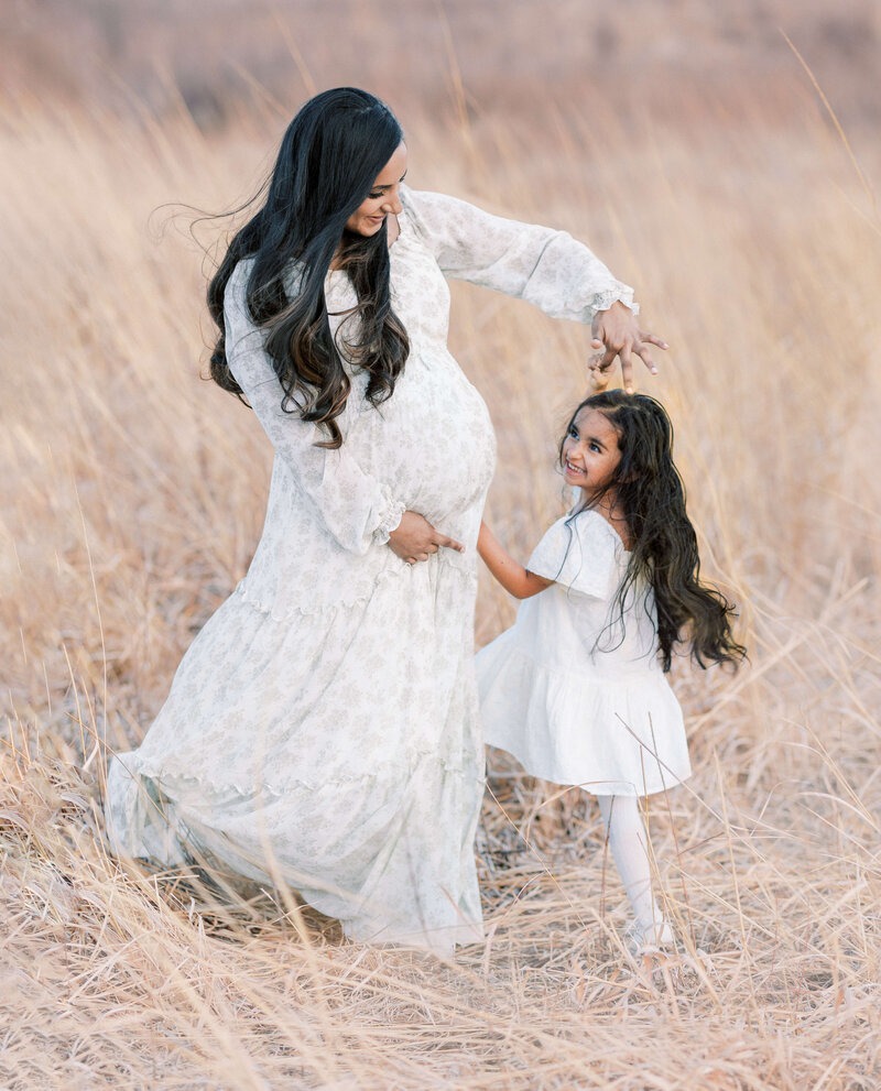 Expecting mother dancing with her young daughter during an outdoor maternity session