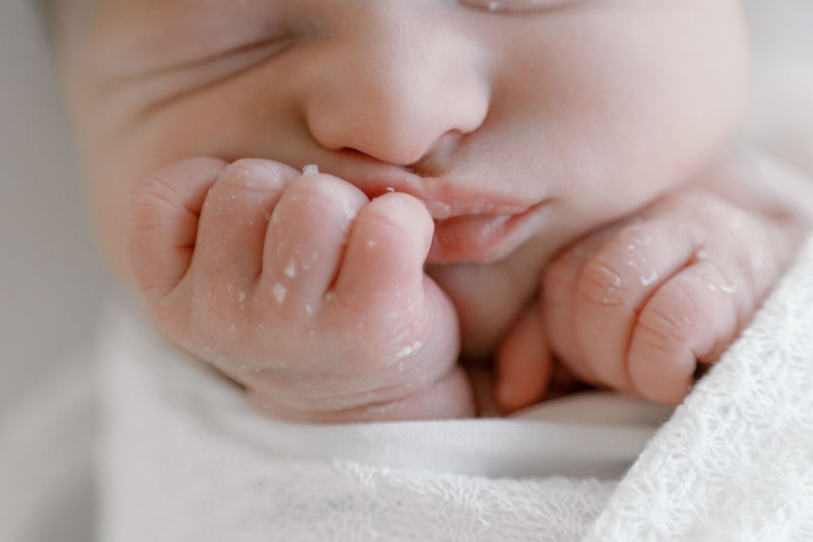 Close-up of a newborn's tiny hands resting near their lips, photographed for an article about food delivery services in the Bay Area